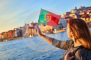 Young woman tourist with portuguese flag enjoying beautiful landscape view on the old town Ribeira historical quarter and river