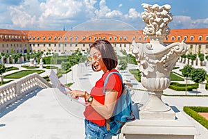 Young woman tourist reading map and admiring amazing view of a flower garden in Bratislava, Slovakia