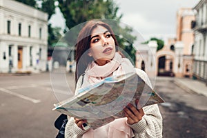 Young woman tourist searching for right way using map in Odessa. Girl lost in city. Traveler going sightseeing