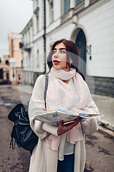 Young woman tourist searching for right way using map in Odessa. Girl lost in city. Traveler going sightseeing