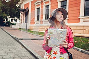 Young woman tourist searching for right way using map in Odessa, Ukraine. Girl lost in city. Traveler going sightseeing