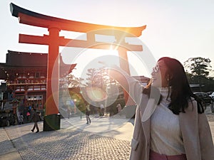 Young woman tourist travel Kyoto, Japan at Fushimi Inari Shrine main gate at sunrise