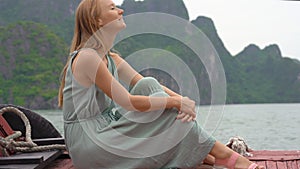 A young woman tourist visits the Halong Bay national park in Vietnam consisting of thousands of small and big limestone