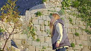 A young woman tourist visits the old town of Kotor in Montenegro. She is enjoying fabulous view of the city climbing