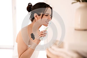 Young woman in towel brushing teeth at home. Morning routine