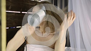 Young woman in towel drying her hair in front of a mirror. Skin care and home Spa