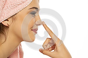 Young woman with towel on her head,  touches her nose