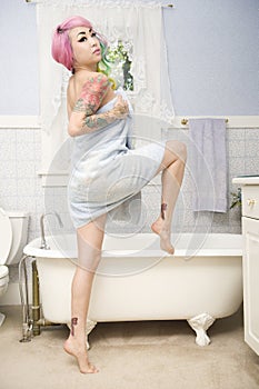 Young woman in towel posing in front of bathtub