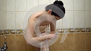 Young woman in towel shaving legs in bathroom, home comfort, depilation