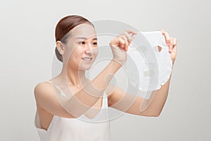 Young woman in a towel tied on her head applying facial moisturizing mask