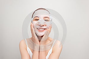Young woman in a towel tied on her head applying facial moisturizing mask