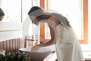 Young woman in towel wash face with tap clean water