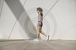 Young woman in tracksuit have rest after workout outside crossing on building background