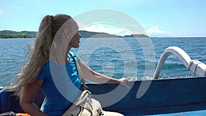 A young woman in a traditional Indonesian boat sails between tropical islands on a sunny day