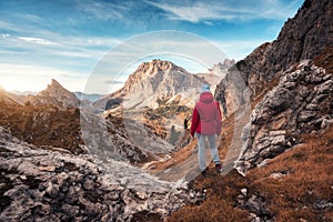 Young woman on the trail looking on high mountain peak at sunset