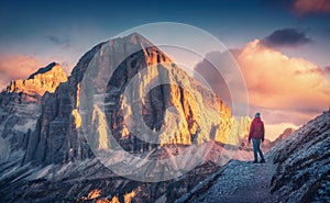 Young woman on the trail looking on high mountain peak at sunset