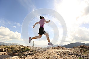 Young woman trail runner running on beautiful mountain peak