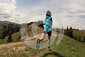 Young woman trail runner running on beautiful mountain peak