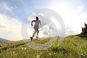 Young woman trail runner running on beautiful mountain peak