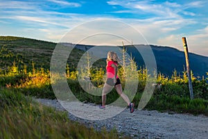 Young woman trail running in mountains at summer