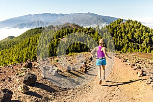 Young woman trail running in mountains on sunny summer day