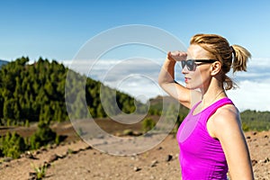 Young woman trail running in mountains on sunny summer day