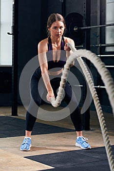 Young Woman Training with Battle Ropes in Gym