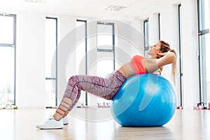 Young woman training with fitball at fitness club.