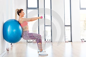 Young woman training with fitball at fitness club.