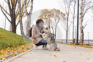 Young woman training her husky dog in autumn park