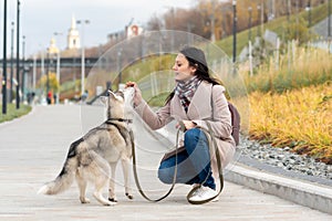 Young woman training her husky dog in city park