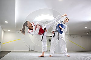 Young woman training martial art of taekwondo with her coach