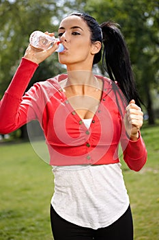 Young woman training in park drinking water