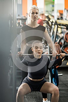 A young woman trains in a gym with a female coach. Deadlift.