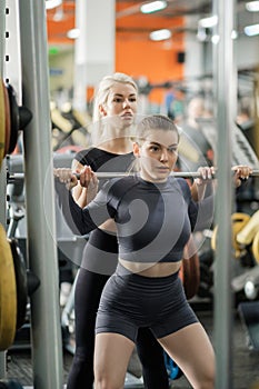 A young woman trains in a gym with a female coach. Deadlift.