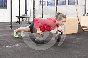 Young woman trains pushups with kettlebells