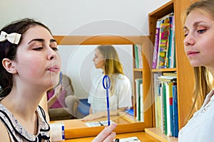 Young woman trains with speech therapy probe in soft focus