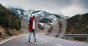 Young woman travel photographer walk on empty mountain road making photo