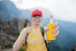 Young woman travel spraying insect repellents on skin with spray bottle during hike in nature top mountain. Skin