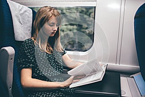 Young woman travel in train. Sit alone and read book. Concious and concentrated on process. Smart woman studying or