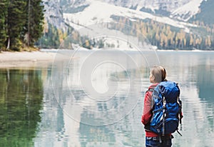 Young woman traveler in Alps mountains looking on a lake. Travel, winter and active lifestyle concept