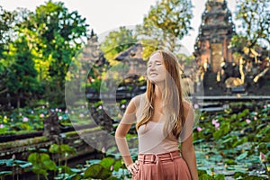 Young woman traveler in the background of Pura Taman Kemuda Saraswati Temple in Ubud, Bali island, Indonesia