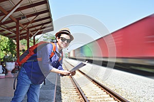 Young woman traveler with backpack standing on train station