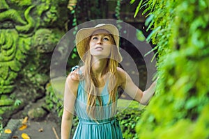 Young woman traveler in a Balinese garden overgrown with moss. Travel to Bali concept