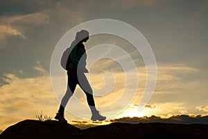 Young Woman Traveler Hiking with Backpack on the Beautiful Rocky Trail at Summer Sunset. Travel and Adventure Concept.