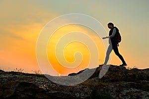 Young Woman Traveler Hiking with Backpack on the Rocky Trail at Warm Summer Sunset. Travel and Adventure Concept.