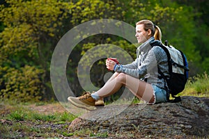 Young woman traveler hiking in summer forest and stopped to have