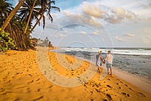 Young woman traveler holding man\'s hand and walking on the beach, Couple on vacation in summer concept