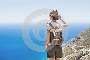 Young woman traveler looking at the sea. Beautiful girl enjoying nature. Summer holiday, vacation, travel, tourism concept