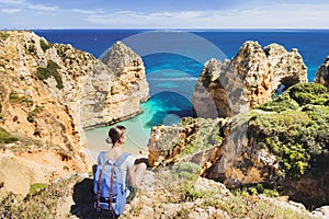 Young woman traveler looking at the sea in Lagos town, Algarve region, Portugal. Travel and active lifestyle concept